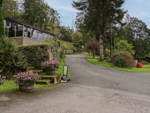 Eine abgeschiedene Holzhütte, umgeben von üppigem Grün und einer kurvenreichen Straße.
