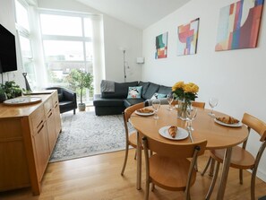 A modern living room with a dining area, a sofa, a coffee table, and a TV. - Seaview in Benllech, Anglesey. (Tyn-y-Gongl)