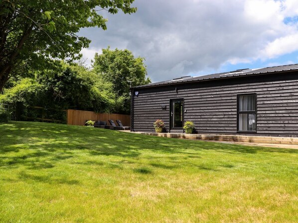 A wooden building with a dark roof, a door, and two windows. There is a grassy lawn in front. - The Goose Shed, Adisham near Wingham, Kent. (Canterbury)