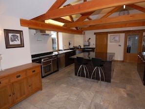 Una cocina amplia con vigas de madera, una isla central, taburetes de bar y una mesa de comedor.