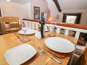 A dining table set with plates, cutlery, and glasses, with a bottle and salt shakers on the table. - Horse Mill Lodge, Taddington (Buxton)