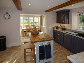 A kitchen with a wooden table, dark cabinets, and a window with a view.