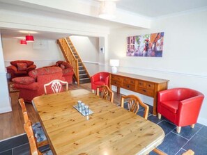 A dining area with a wooden table and chairs, a staircase, and red furniture. - Arfryn: A Charming Retreat in Bethesda (Bangor)