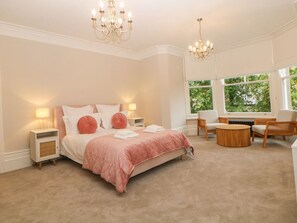 A bedroom with a bed, bedside tables, a round coffee table, and a window with a view.