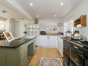 A kitchen with white cabinets, a black countertop, a microwave, and a stove. - Holly Cottage, Conwy (Conwy)