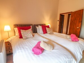 Hotellihuone, jossa on suuri sänky, kaksi yöpöytävalaisinta, puuovi ja patteri.
