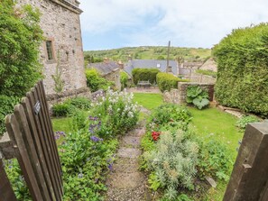 A stone building with a garden pathway leading to a grassy area. - Holly Cottage, Winster (Matlock)