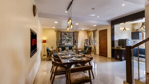 A dining area with a table set for six, a ceiling fan, and a view of the outdoors. - ELIVAAS The Nakshatra Serene 3BHK Villa (Sukha)