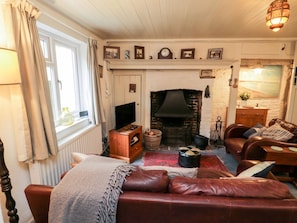 Ein gemütliches Wohnzimmer mit Kamin, Ledersofa und Fernseher.