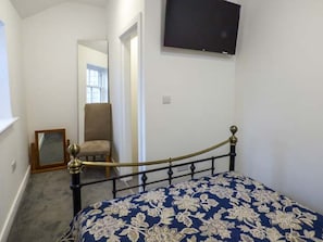A bedroom with a bed, a chair, a television, and a mirror.