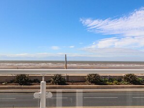A coastal road with a guardrail, a beach in the distance, and a clear sky. - 26 North Promenade, Cleveleys. (Thornton-Cleveleys)