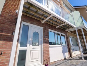 A two-story building with a brick facade, white-framed windows, and a balcony with a glass railing. - 26 North Promenade, Cleveleys. (Thornton-Cleveleys)