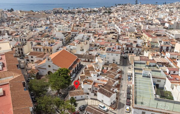Zona urbana densamente poblada con edificios residenciales y comerciales, una iglesia destacada con techo rojo y un campo deportivo.