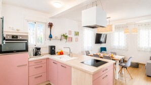Une cuisine moderne avec des meubles de couleur rose, un four encastré et un coin repas comprenant une table et des chaises.
