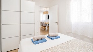 Une chambre à coucher comprenant un lit, une armoire, une salle de bain et un coin repas visible à travers une porte ouverte.