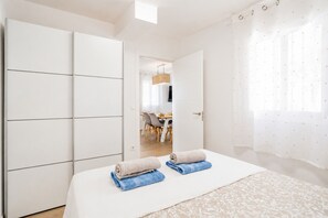 A bedroom with a bed, a wardrobe, a bathroom, and a dining area visible through an open door. - Cubo's Casa Nerja Roof Terrace / near beach / air conditioning / free wifi (Nerja)