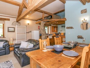 Ein gemütliches Wohnzimmer mit Ledersofa, Holzesstisch und Blick zur Küche.