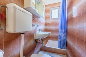 Een douche, handdoeken, zeep, toiletpapier