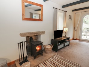 A cozy living room with a fireplace, a television, and a large mirror on the wall. - Mill Cottage, Buckden (Skipton)