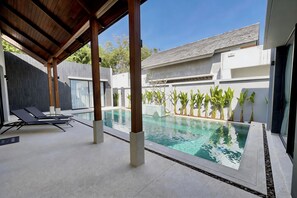 Una piscina al aire libre, sillones reclinables de piscina