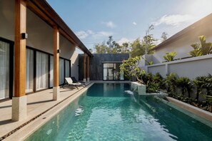 Una piscina al aire libre, sillones reclinables de piscina