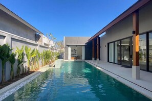 Una piscina al aire libre, sillones reclinables de piscina