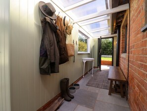 A narrow corridor with a skylight, a coat rack with hats, boots, and a small table. - The Alms House East is in Forthampton (Gloucester)