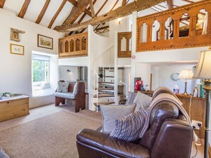 A spacious living area with a leather sofa, a wooden staircase, and a high ceiling with exposed beams. - The Old Chapel, Crich (Matlock)