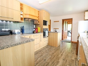 A kitchen with wooden cabinets, granite countertops, a microwave, and an oven. - Dragonfly Lodge, Whinburgh (Dereham)