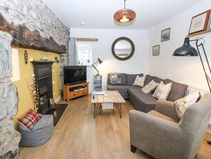 Ein gemütliches Wohnzimmer mit Steinwand, Kamin, Sofa, Couchtisch und Fernseher.