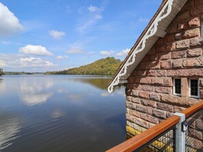 Ein Steinhaus mit Holzgeländer mit Blick auf einen stillen See.