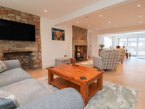 A living room with a stone fireplace, a flat-screen TV, and a sofa. - Vine Cottage, Pilling (Preston)