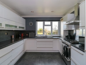 Una cocina moderna con armarios blancos, encimera negra, estufa y ventana con vistas.