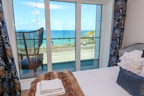 A bedroom with a large window, a bed, a chair, and a view of the ocean. - 17 Cliff Edge Newquay Cornwall (Newquay)