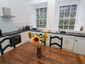 Eine moderne Küche mit weißen Schränken, einem Holzespeisetisch und einer Vase mit Sonnenblumen.