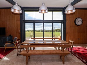 A dining area with a wooden table, benches, pendant lights, and a view of the outdoors. - Brock House, in Northallerton. (Northallerton)