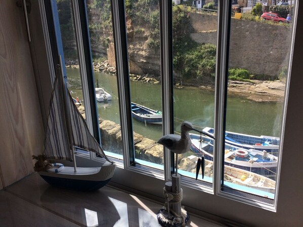 Vista da janela de um rio com barcos, um modelo de veleiro e uma estatueta de gaivota.