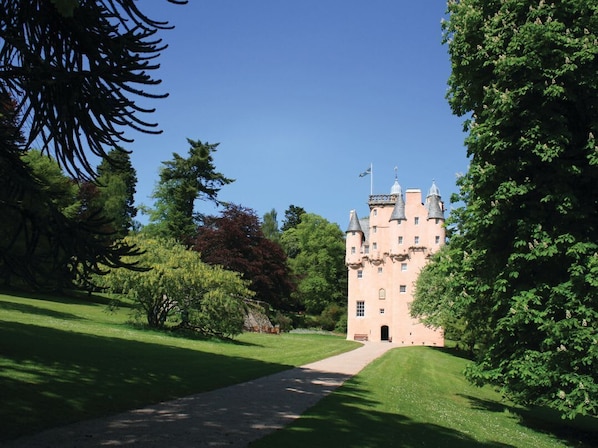A castle-like building with a central tower, surrounded by lush greenery and a clear sky. - North Mains Cottage, Alford, Aberdeenshire (Alford)