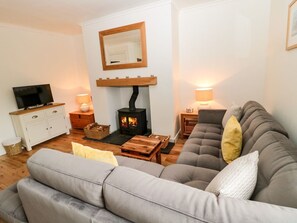 Ein Wohnzimmer mit Sofa, Fernseher, Kamin und einem Spiegel an der Wand.