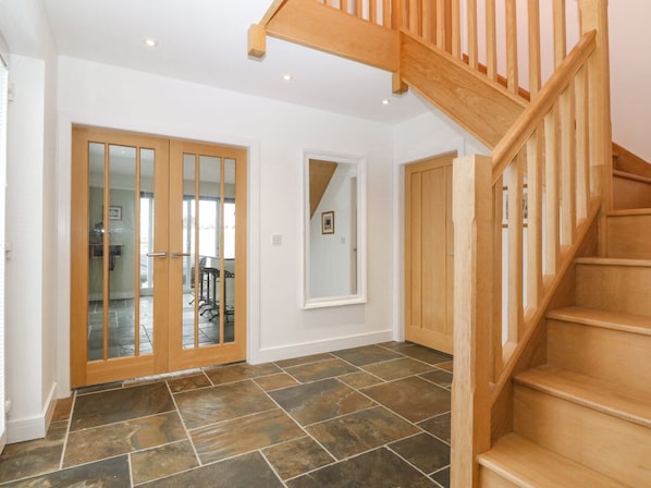 A spacious interior with a wooden staircase, a tiled floor, and a large sliding glass door leading to an outdoor area.