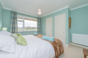 A bedroom with a bed, a window, a door, and a radiator. - Pear Tree Cottage, Pulverbatch (Shrewsbury)