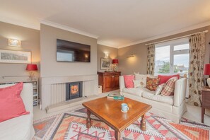 A living room with a fireplace, a sofa set, a coffee table, and a television mounted on the wall. - Pear Tree Cottage, Pulverbatch (Shrewsbury)