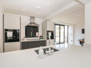 A modern kitchen with a central island, stainless steel appliances, and a large window. - Bailey house, Pocklington (Driffield)
