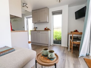 A compact living space with a kitchenette, a dining area, and a seating area with a small table and two mugs. - Charming The Cabin Retreat in Swanage (Swanage)
