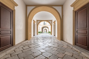A corridor with stone flooring, wooden doors, and arches. - Palazzo Sambuca Charming by Wonderful Italy (Palermo)