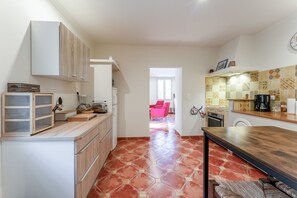 A kitchen with a wooden countertop, cabinets, and a tiled floor.
