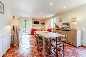A dining area with a wooden table and chairs, a kitchen with a wooden countertop, and a TV mounted on the wall.