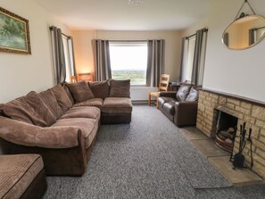 A living room with a sectional sofa, a fireplace, and a view through the window.