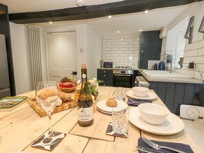 A dining area with a table set for two, a bottle of wine, and a book.