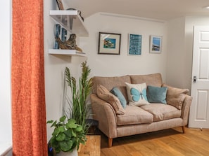 Una sala de estar con un sofá color beige, una mesa de centro de madera y una planta en maceta.